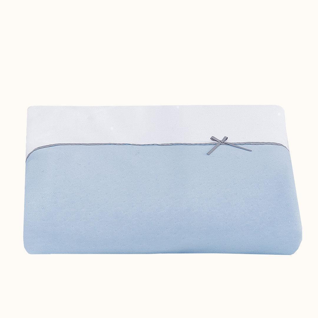 Lençol de berço azul e branco para bebé, com laço decorativo delicado.