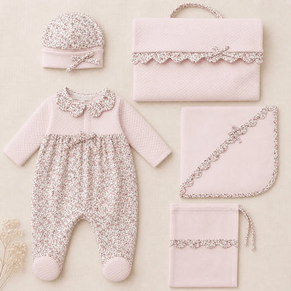 Conjunto enxoval de recém-nascido rosa claro com estampa floral, incluindo macacão, touca, manta e bolsa.