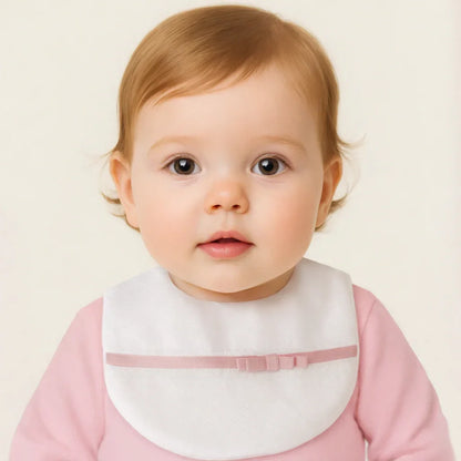 bebê usando babador branco com laço rosa, roupa rosa, fundo claro, moda infantil confortável
