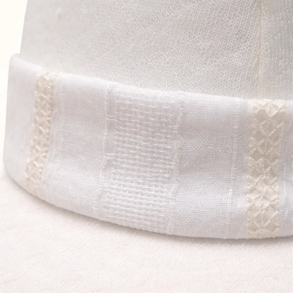 detalhe do gorro bege em algodão com detalhe bordado, confortável para recém-nascidos.