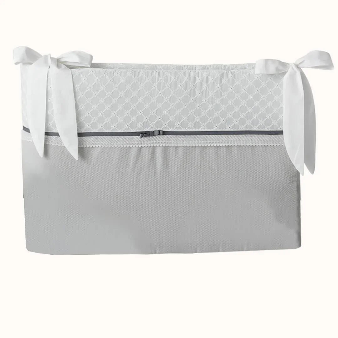 Resguardo de berço cinza com laços brancos e detalhe rendado, enxoval de bebé elegante.