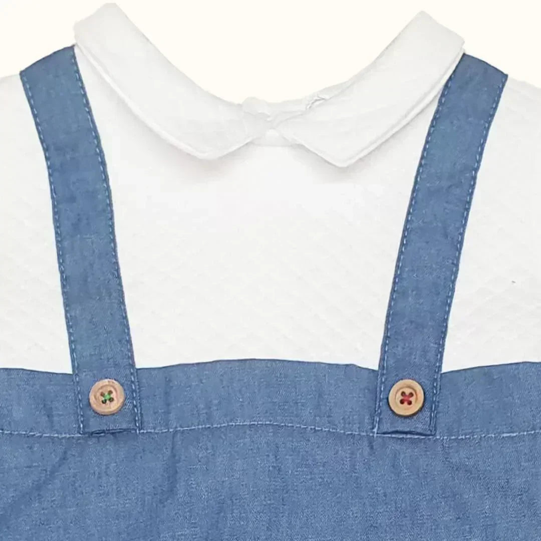 Macacão denim azul claro para bebé com botões de madeira e camisa branca de algodão.