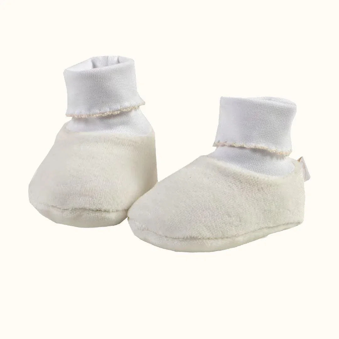 Pantufas de bebé bege em tecido macio, com cano alto branco, para recém-nascidos.