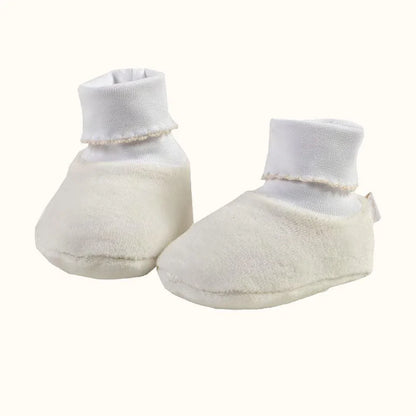 Pantufas de bebé bege em tecido macio, com cano alto branco, para recém-nascidos.