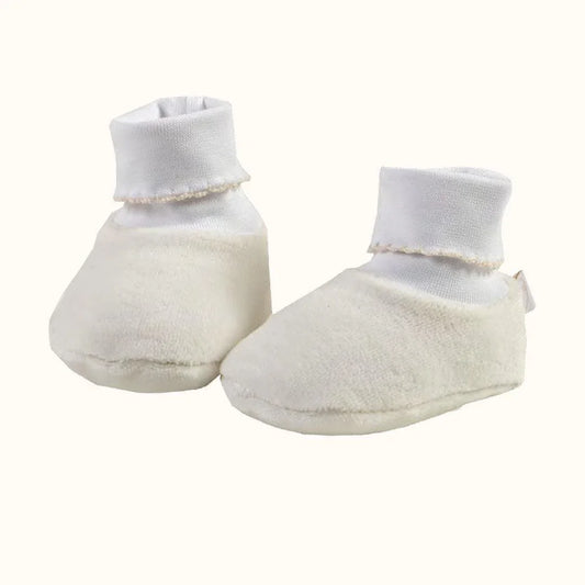 Pantufas de bebé bege em tecido macio, com cano alto branco, para recém-nascidos.