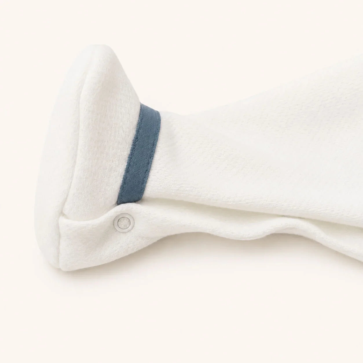 Pormenor da perna do babygrow bege com detalhe azul, ideal para recém-nascidos