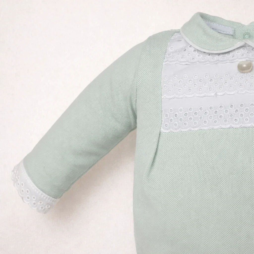 pormenor de babygrow para bebé verde claro em tricô com gola e detalhes rendados brancos