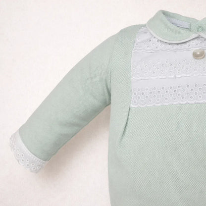 pormenor de babygrow para bebé verde claro em tricô com gola e detalhes rendados brancos