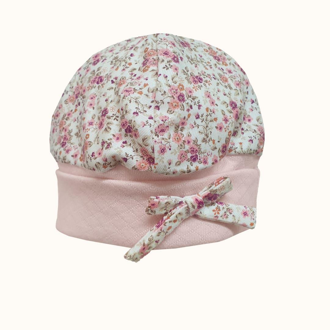 Touca de bebê em algodão, rosa claro com estampa de florzinhas e laço decorativo.