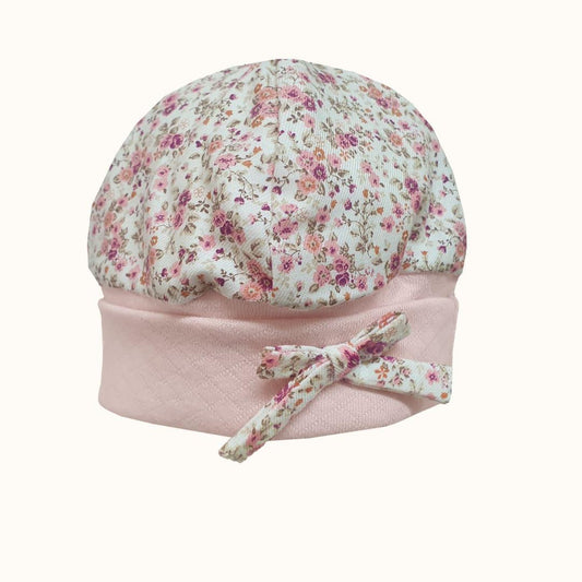 Touca de bebê em algodão, rosa claro com estampa de florzinhas e laço decorativo.