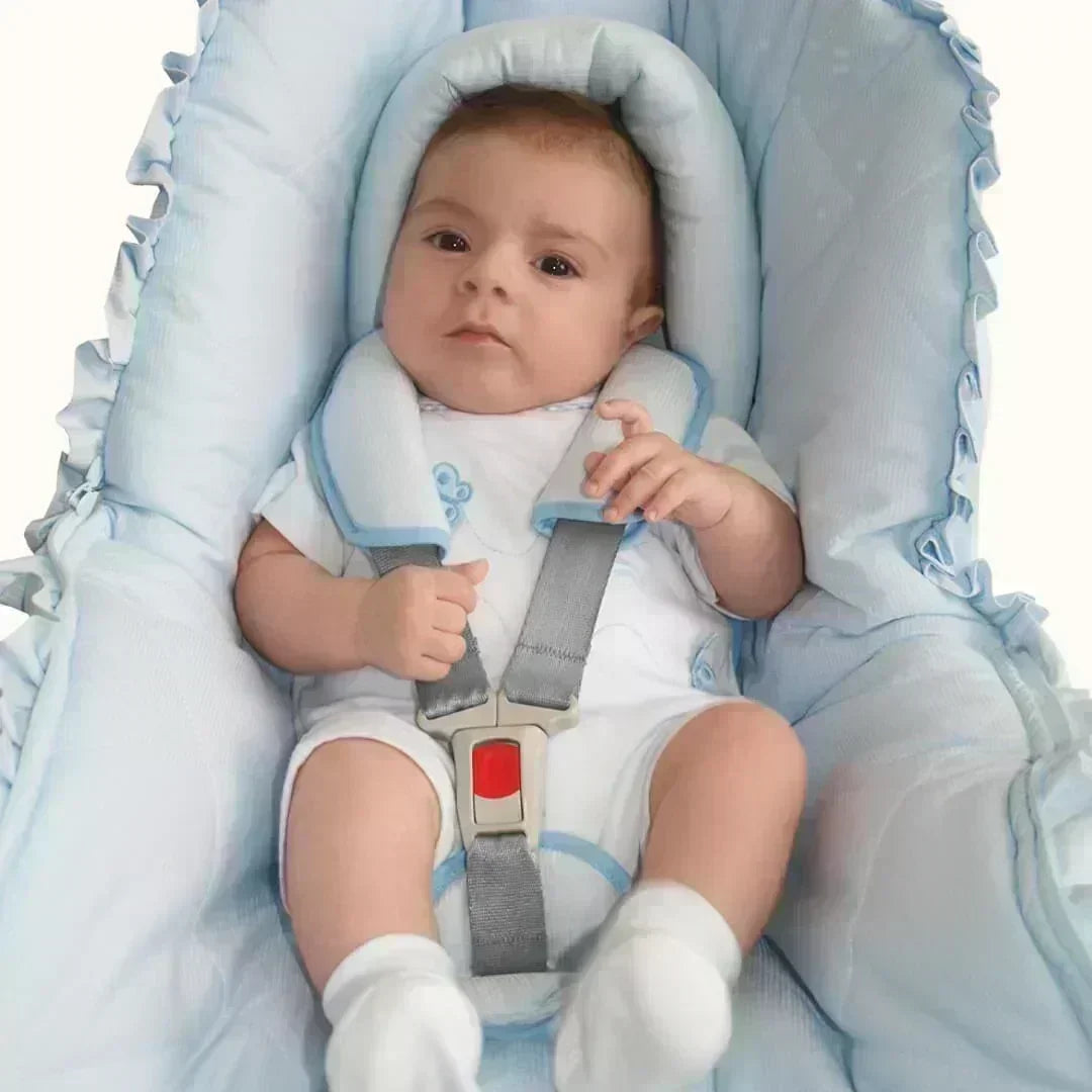 Bebê em assento infantil com redutor e protetores de cinto azul, conforto e segurança