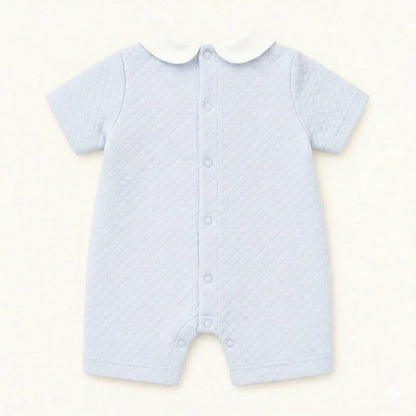 Macacão de bebê azul claro matelassê com gola branca e botões frontais, roupa confortável para recém-nascido.