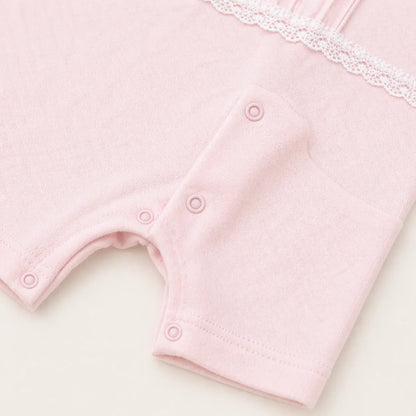 Detalhe de macacão de bebê rosa com botões de pressão e renda, roupa confortável para recém-nascido