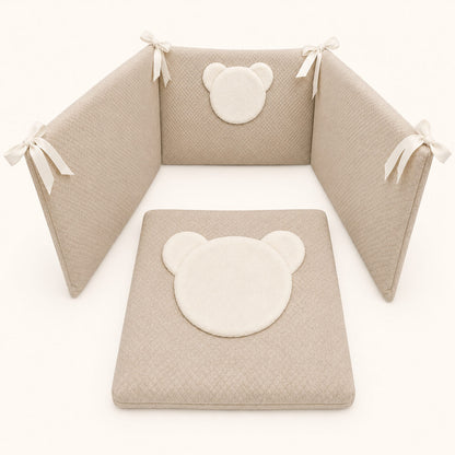 Conjunto de berço com protetores e colchão em tons neutros, com detalhes de urso fofo e laços