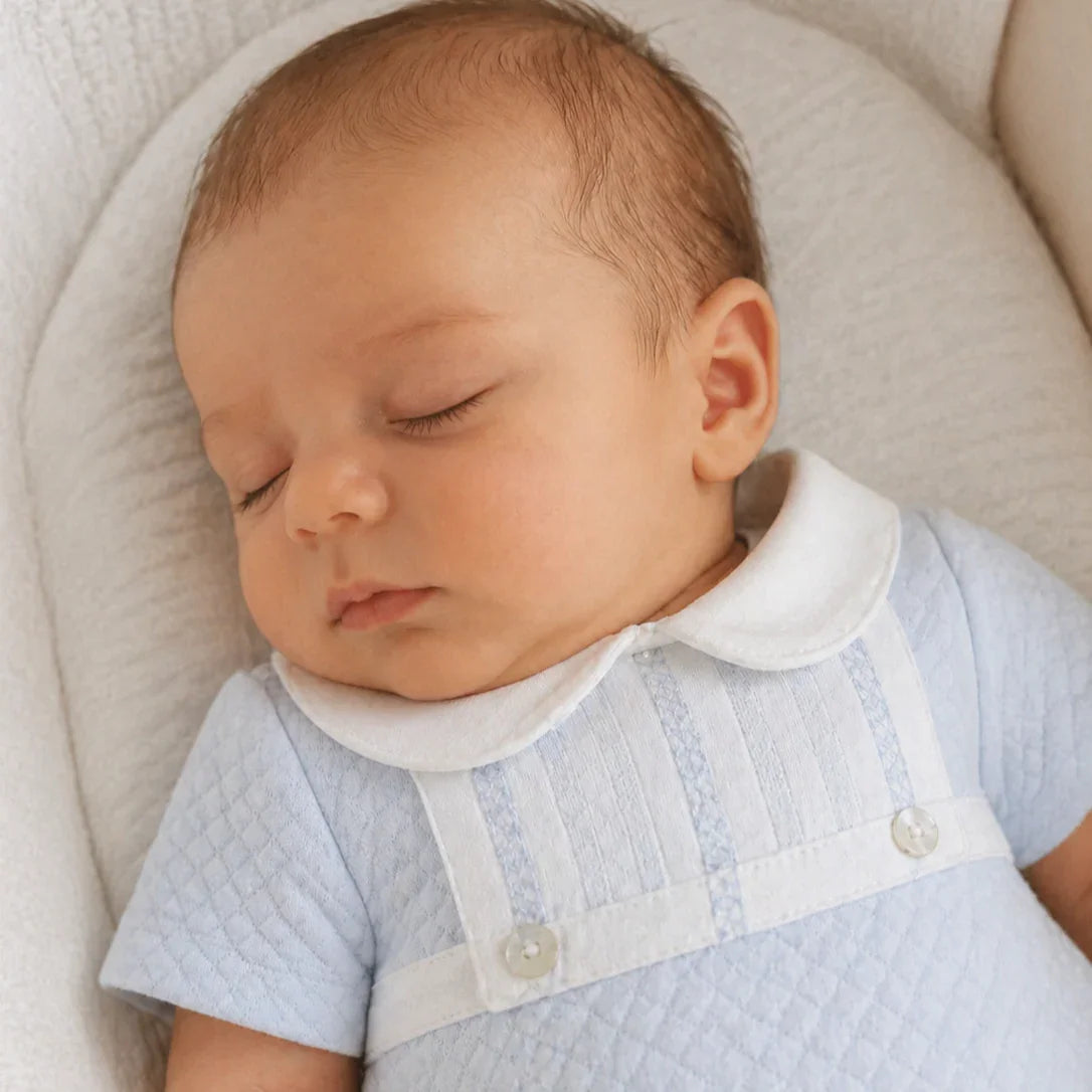 bebê dormindo com macacão azul claro de algodão, gola branca, conforto e qualidade