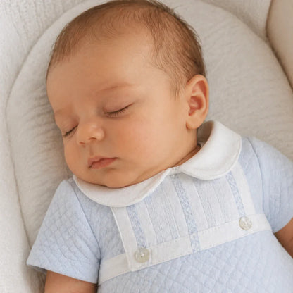 bebê dormindo com macacão azul claro de algodão, gola branca, conforto e qualidade