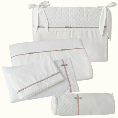 Enxoval de berço branco com detalhes rosa velho, laços e textura delicada para bebê