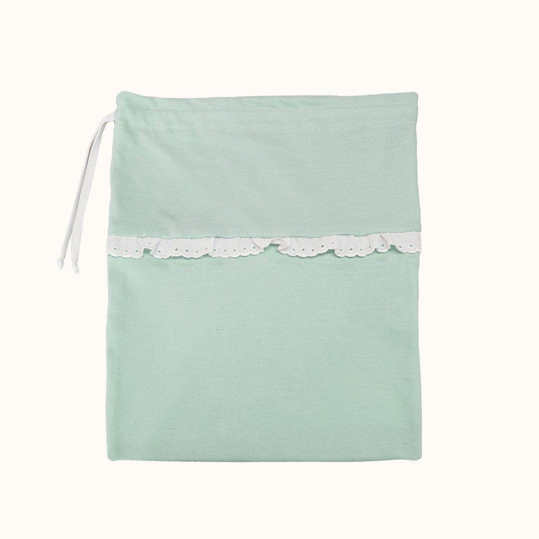 Saquinho para roupa de bebê em tecido verde claro com detalhe em renda branca e fecho de cordão.