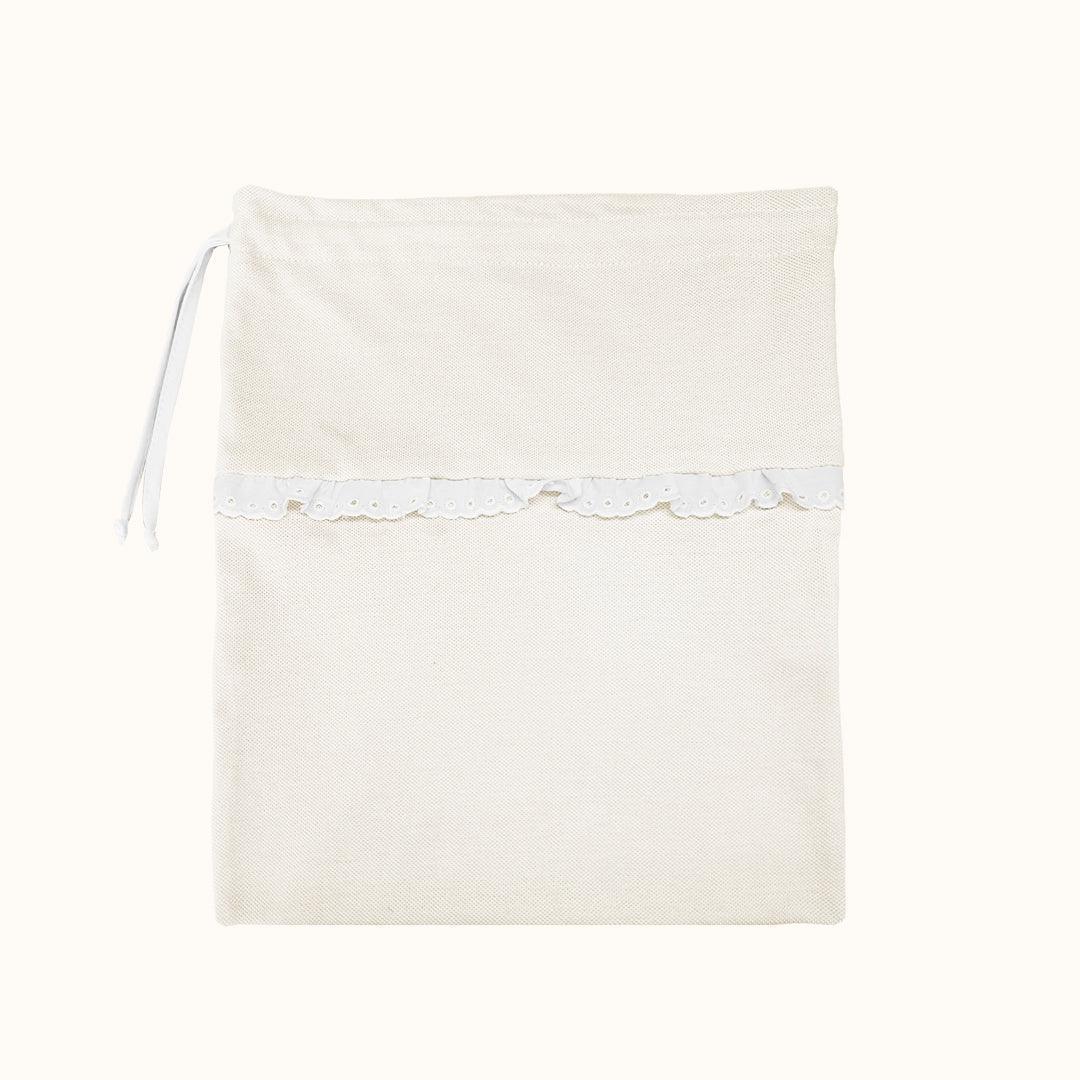 Saquinho de tecido bege para roupa de bebé com renda delicada e cordão lateral.