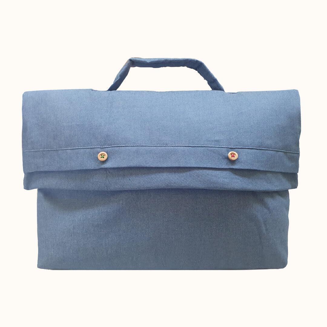 Saquinho para roupa de bebé em denim azul claro com alça e botões decorativos.