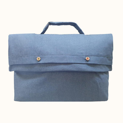 Saquinho para roupa de bebé em denim azul claro com alça e botões decorativos.